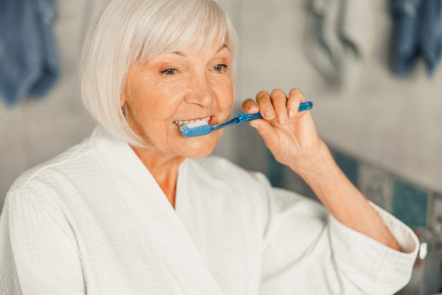Senior lady brushing teeth in the morning Senior lady brushing teeth in the morning