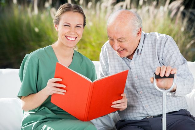 Portrait Of Happy Female Nurse Reading Book For Senior Man A Guide To Finding The Best Memory Care
