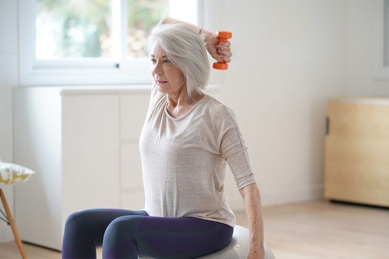 Attractive elderly woman exercising at home with swiss ball Attractive elderly woman exercising at home with swiss ball