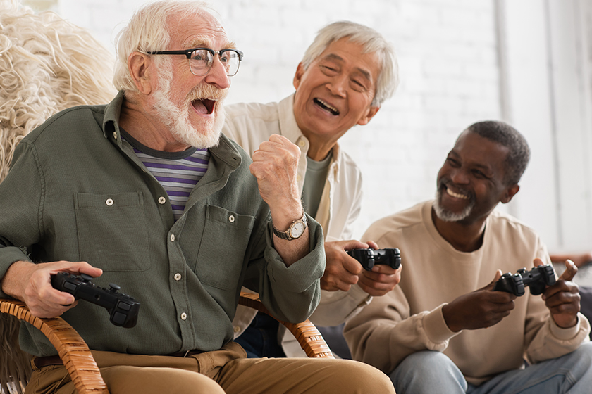 Excited senior man showing yes gesture near multiethnic friends