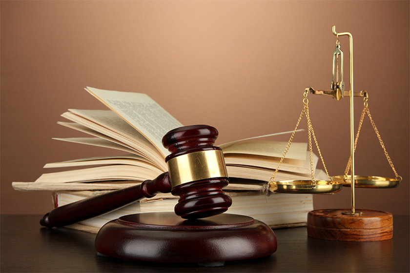 Golden scales of justice, gavel and books on brown background