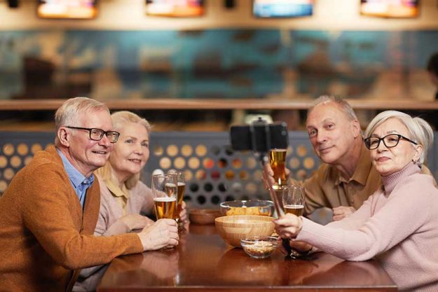 Group of modern senior people taking selfie photo while drinking beer