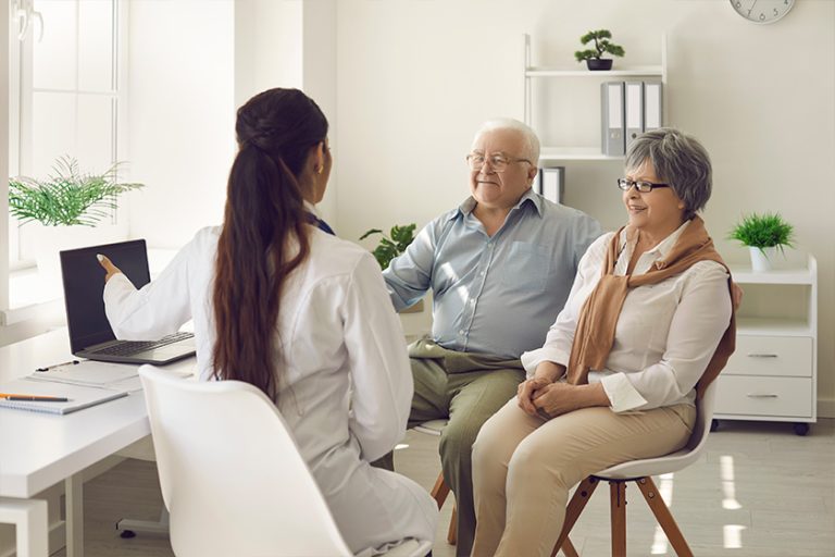 Happy mature couple and their doctor communicating while using laptop Happy mature couple and their doctor communicating while using laptop