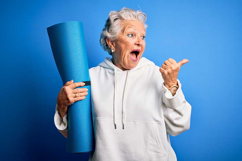Senior beautiful sporty woman holding mat for yoga