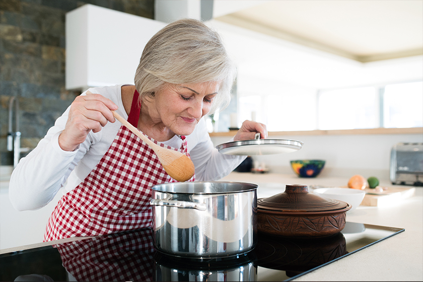 https://www.discoveryvillages.com/wp-content/uploads/2022/08/senior-woman-in-the-kitchen-cooking-mixing-food-in-a-pot.jpg