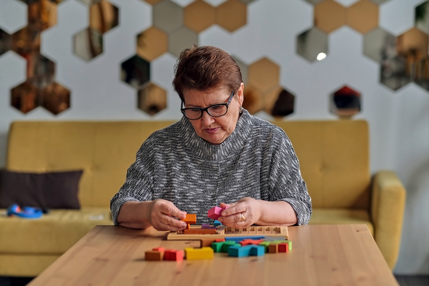 Activity can improve brain function. Elderly woman sitting at table and sorting jigsaw puzzle pieces, free space game The Myths About Memory Care Facilities In Atlantic Beach, FL You Should Know The Truth