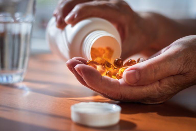 Senior woman taking omega 3 pills from bottle. Health care conce Senior woman taking omega 3 pills from bottle. Health care conce