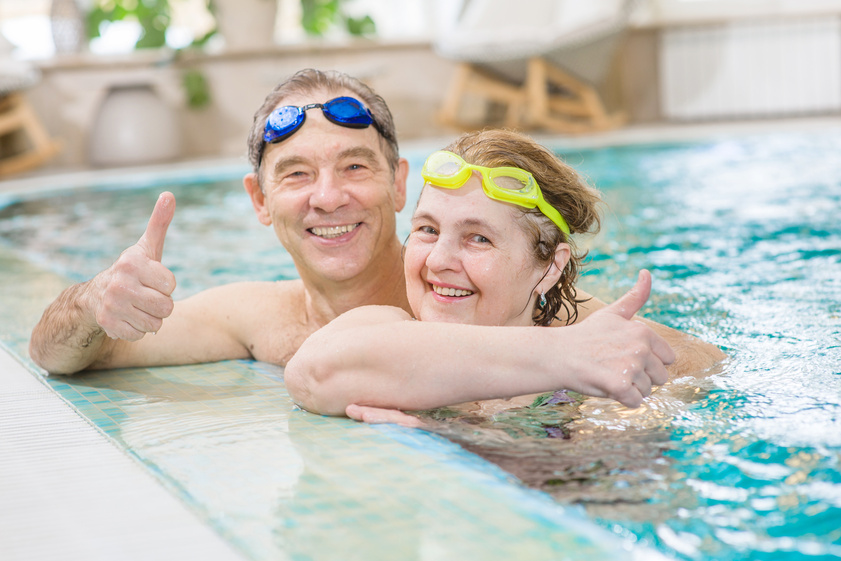 happy elderly couple in the pool showing thumbs up happy elderly couple in the pool showing thumbs up