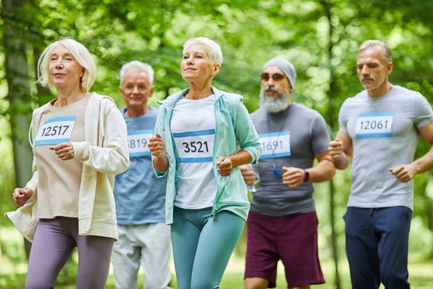 Active senior men and women spending summer day time together in park running marathon Active senior men and women spending summer day time together in park running marathon