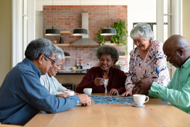 Group of diverse senior male and female friends doing puzzles at Exploring Senior Living Apartments In Frisco, TX