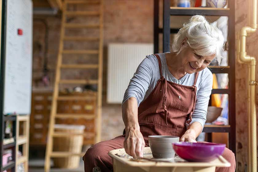 Hand made ceramics are formed by a mature woman on a potters wheel