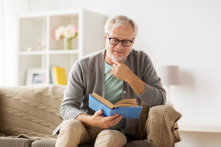 senior man on sofa reading book at home Is Learning New Languages After 50s A Good Idea?
