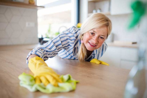 Portrait of senior woman cleaning kitchen counter indoors at home. Portrait of senior woman cleaning kitchen counter indoors at home.