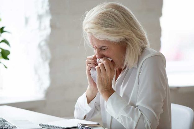 Unhappy 60 years old businesswoman sneeze close up