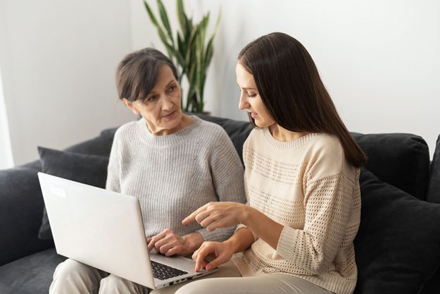 An adult daughter is teaching to senior mother how to pay bill online An adult daughter is teaching to senior mother how to pay bill online