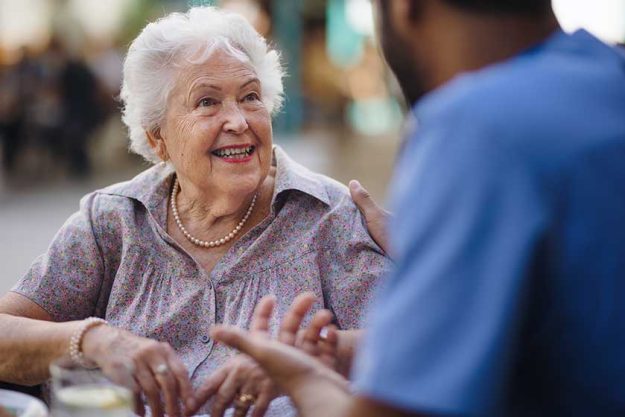 Caregiver talking with his client at cafe, having nice time together.