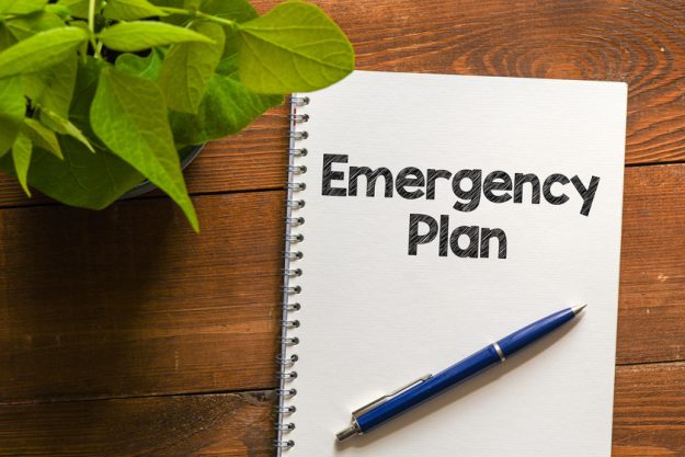 EMERGENCY PLAN text written in an office notebook on a wooden ta