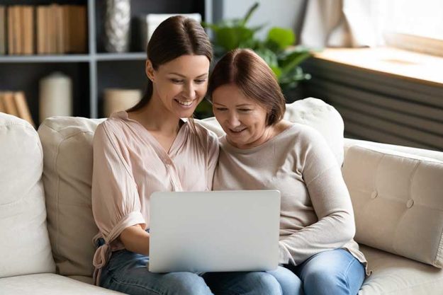 Happy adult daughter and mature mother using laptop together Happy adult daughter and mature mother using laptop together,