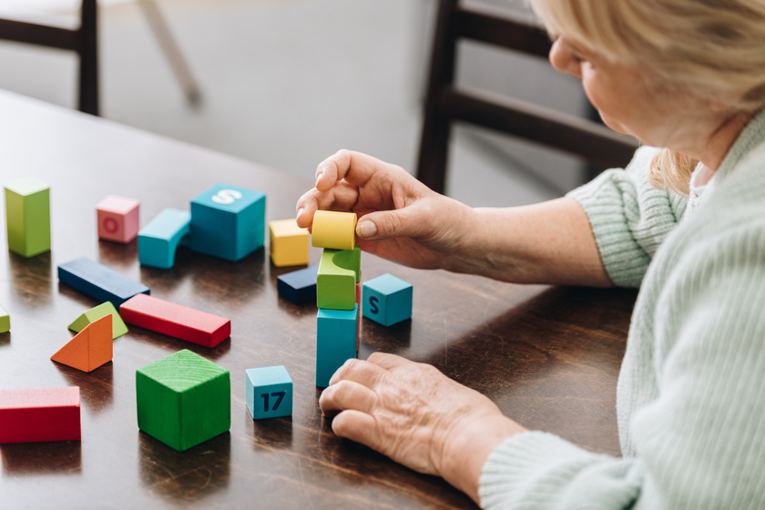 senior woman playing with wooden cubes on table Helping Your Loved Ones With Dementia Transition To Memory Care Near Lake Worth, TX