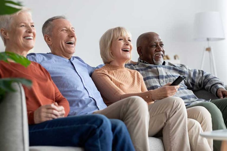 Multiracial friends senior people watching TV and laughing