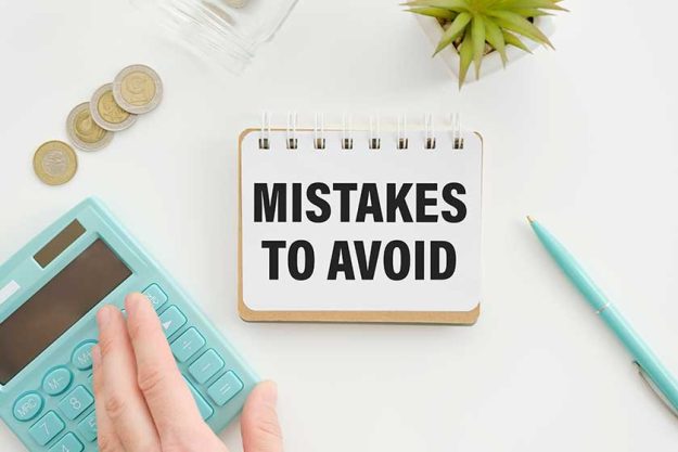 Notepad with text Mistakes To Avoid lying on financial tables with a pen Notepad with text Mistakes To Avoid lying on financial tables with a pen