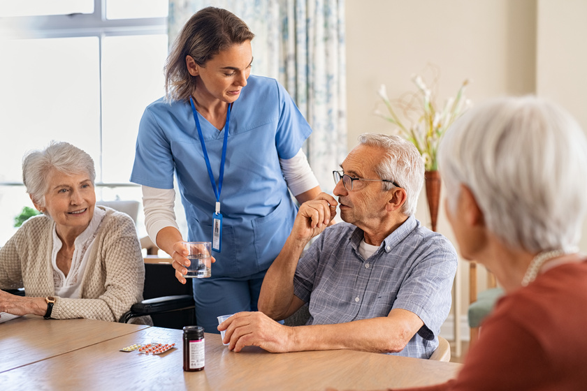 Nurse helping senior man to take his daily medicine at hospice