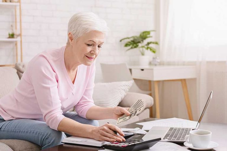 Senior woman with calculator counting dollar money at home Senior woman with calculator counting dollar money at home