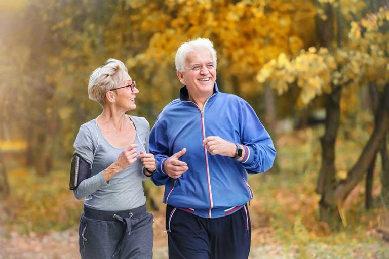 Smiling senior active couple jogging together in the park