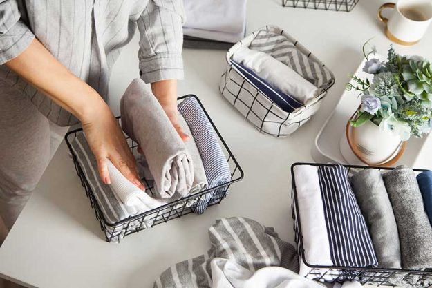 Neatly folded clothes in the metal black baskets for wardrobe Neatly folded clothes in the metal black baskets for wardrobe