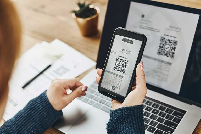 Woman scanning QR code from invoice to make payment using fast secure payment system
