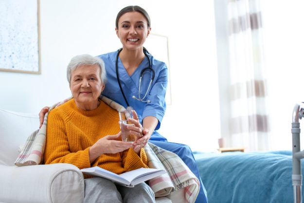 Care worker giving water to elderly woman in geriatric hospice 4 Reasons Why Touring A Senior Living Community In Estero, FL Is A Must