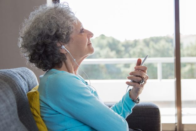 Peaceful elderly woman wearing earphones enjoying music Peaceful elderly woman wearing earphones enjoying music
