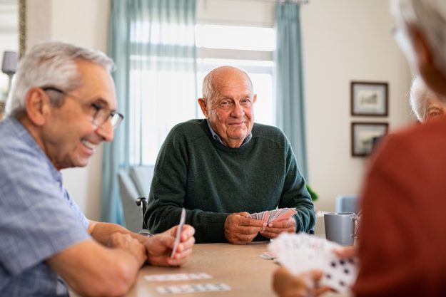 Senior joyful friends playing cards together Senior joyful friends playing cards together