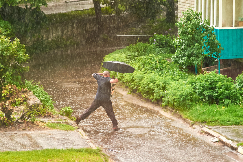 A man with an umbrella jumps over a puddle during heavy rain in summer Five Reasons Why Seniors Refuse To Be Evacuated Before A Hurricane Happens In Naples, FL?