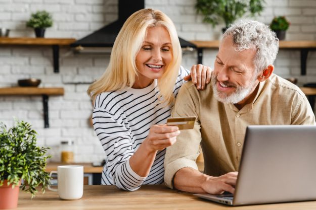 Middle aged smiling couple doing some online shopping at home