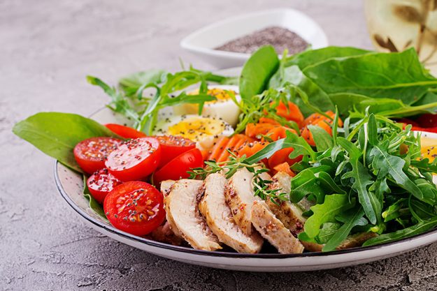 Plate with a keto diet food. Cherry tomatoes, chicken breast, eggs, carrot, salad with arugula and spinach Plate with a keto diet food. Cherry tomatoes, chicken breast, eggs, carrot, salad with arugula and spinach