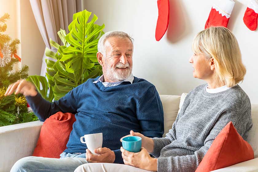 Senior couple man and woman reading a book and drinking coffee tea sitting on sofa Senior couple man and woman reading a book and drinking coffee tea sitting on sofa