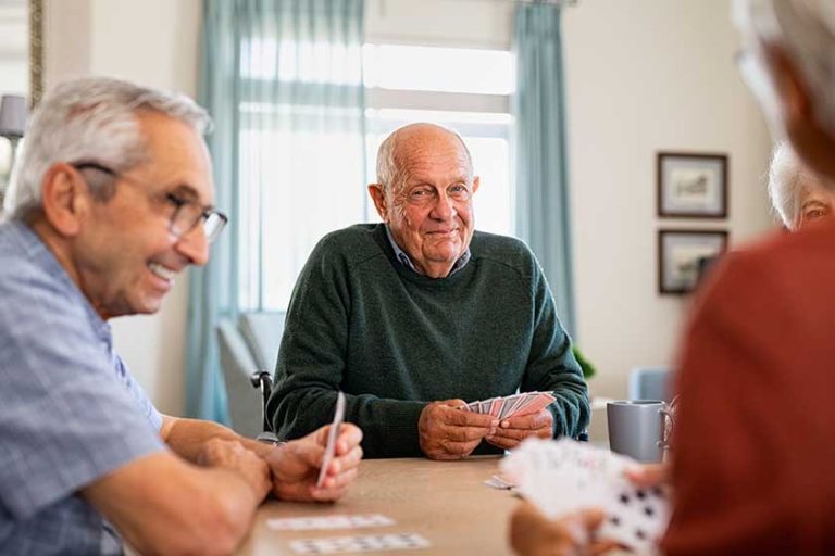 Senior joyful friends playing cards together