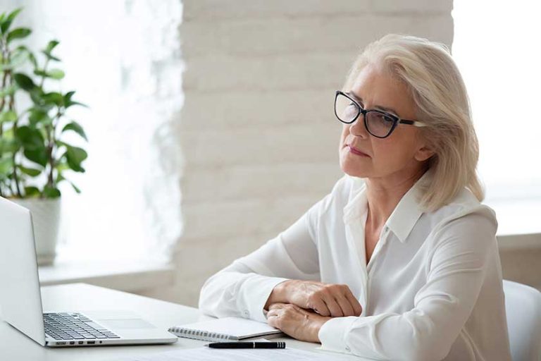 Thoughtful 60 years old businesswoman using laptop business vision.