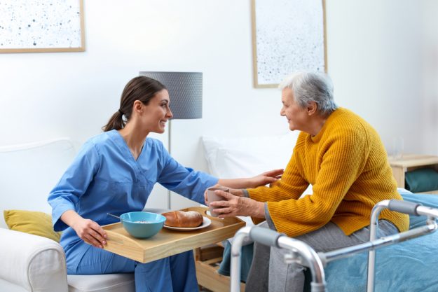 Care worker serving dinner for elderly woman in geriatric hospic Type A Vs. B Assisted Living Facilities In Grapevine, TX: What's The Difference?