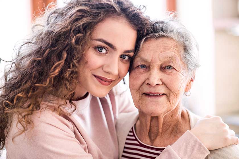 A teenage girl with grandmother at home, hugging. A teenage girl with grandmother at home, hugging.