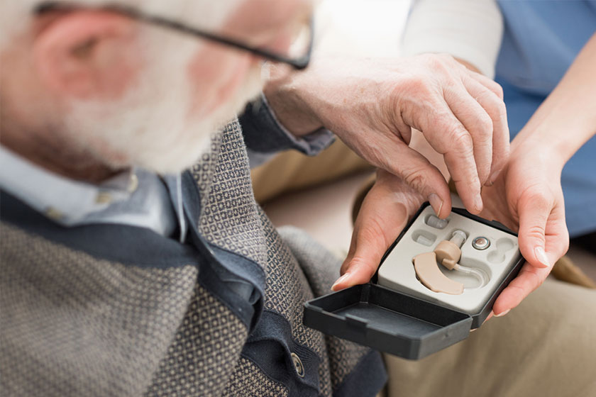 High angle view of elderly man looking at box with hearing aid