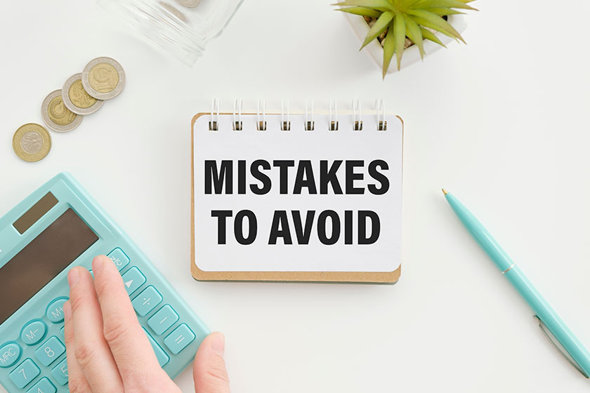 tepad with text Mistakes To Avoid lying on financial tables with a pen
