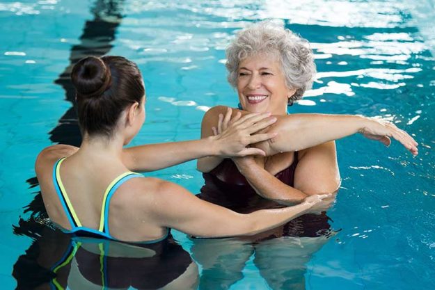 Senior woman stretching in pool