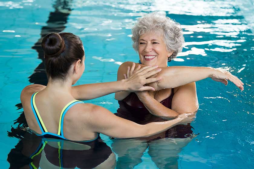 Senior woman stretching in pool