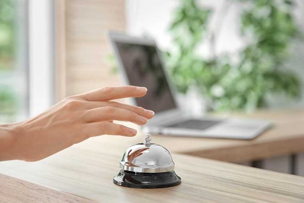 Woman ringing service bell on reception desk in hotel Woman ringing service bell on reception desk in hotel