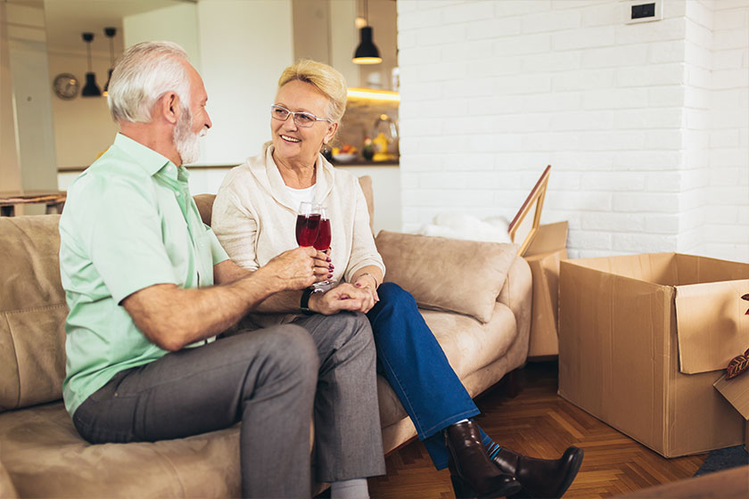 Cheerful senior couple moving into new home smiling at each other