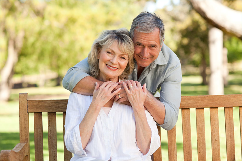 Elderly man hugging his wife who is on the bench Elderly man hugging his wife who is on the bench