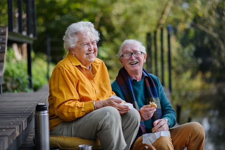 Happy senior couple having picnic and resting near lake Happy senior couple having picnic and resting near lake