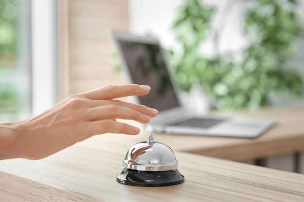 Woman ringing service bell on reception desk Woman ringing service bell on reception desk